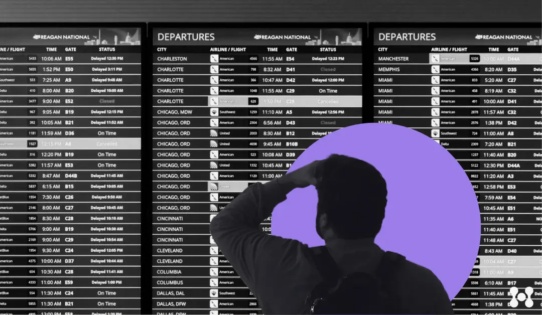 A man looks at a flight information board in an airport, with his hand on his head worried and wondering where his friend's flight may be in the course of it's journey.