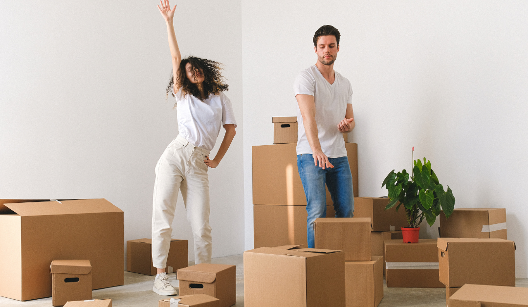 A couple surrounded by packing boxes takes a moment to dance.