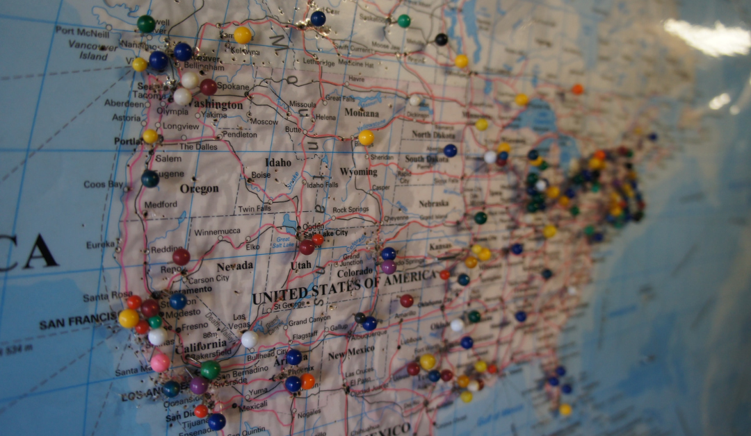 Map of the United States displaying travel routes and clusters of many-colored pushpins.