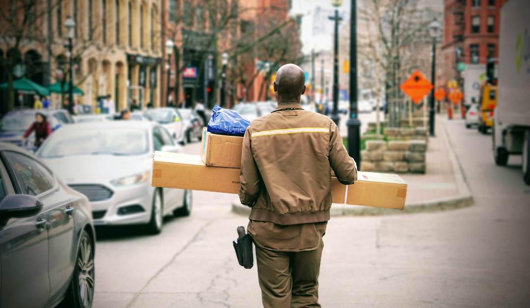 A deliveryman walked down a city street carrying multiple packages.